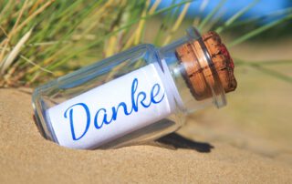 Eine Flasche am Strand mit der Aufschrift Danke.
